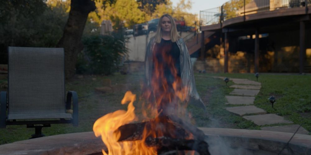 Meg Groves burning a letter in a firepit. This photo is a clip of her new music video, "Thank You Letter."